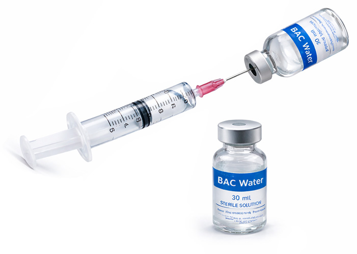 Syringe injecting BAC water along the glass wall of a peptide vial
